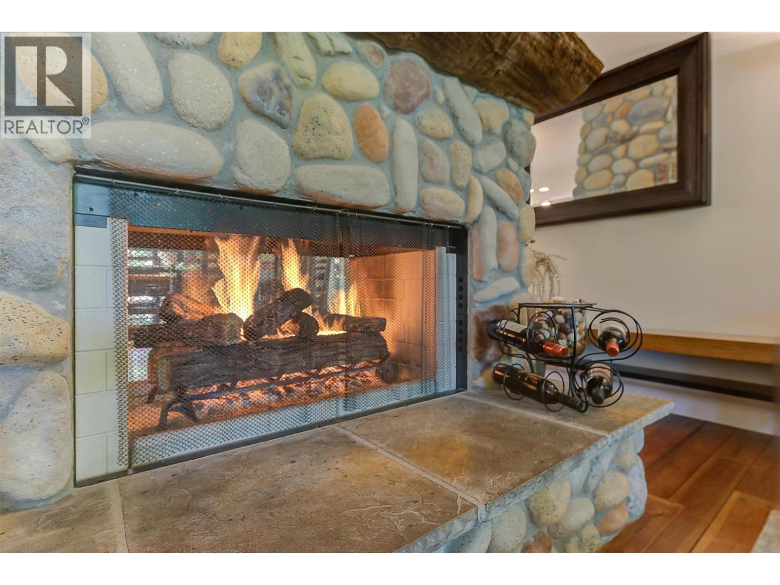Dual side gas fireplace between living and dining rooms - 5127 Luckett Court, Kelowna, BC - Indoor Photo Showing Other Room