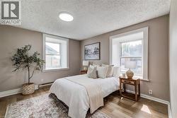 Bedroom with wood finished floors, a baseboard heating unit, and a textured ceiling -