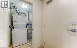Laundry area with light wood-style flooring, stacked washer and clothes dryer, and electric water heater -