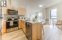 Kitchen featuring stainless steel appliances, backsplash, light brown cabinetry, a peninsula, and light wood-style flooring -