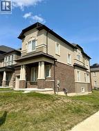 View of property exterior with stucco siding, a lawn, brick siding, and covered porch -