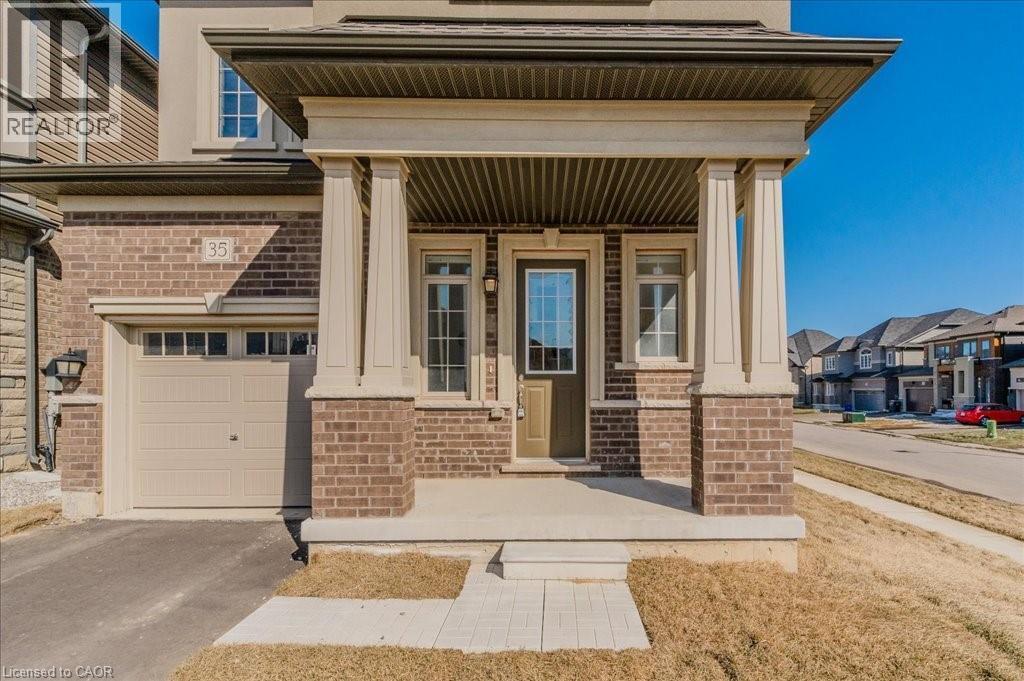Entrance to property featuring covered porch, brick siding, asphalt driveway, a garage, and a residential view - 35 Hitchman Street, Paris, ON - Outdoor With Facade
