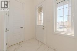 Doorway featuring plenty of natural light and marble finish flooring -