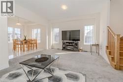 Carpeted living area with stairway and baseboards -