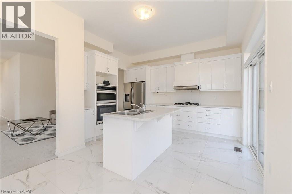 Kitchen with a kitchen bar, white cabinetry, an island with sink, stainless steel appliances, and light marble finish flooring - 35 Hitchman Street, Paris, ON - Indoor Photo Showing Kitchen With Double Sink