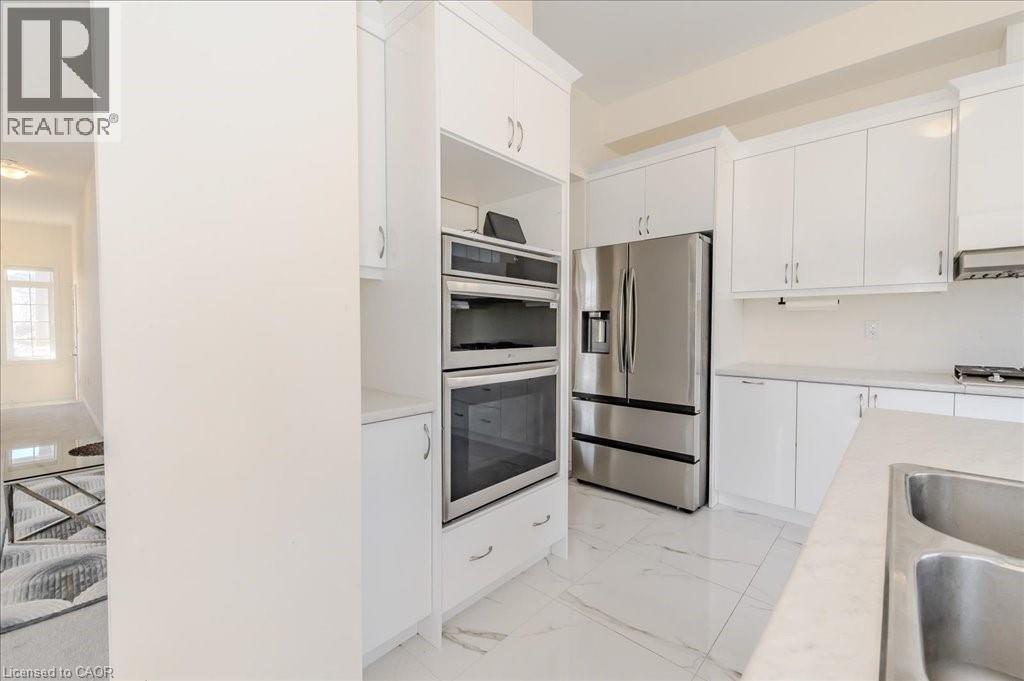 Kitchen featuring appliances with stainless steel finishes, light countertops, light marble finish flooring, white cabinets, and under cabinet range hood - 35 Hitchman Street, Paris, ON - Indoor Photo Showing Kitchen