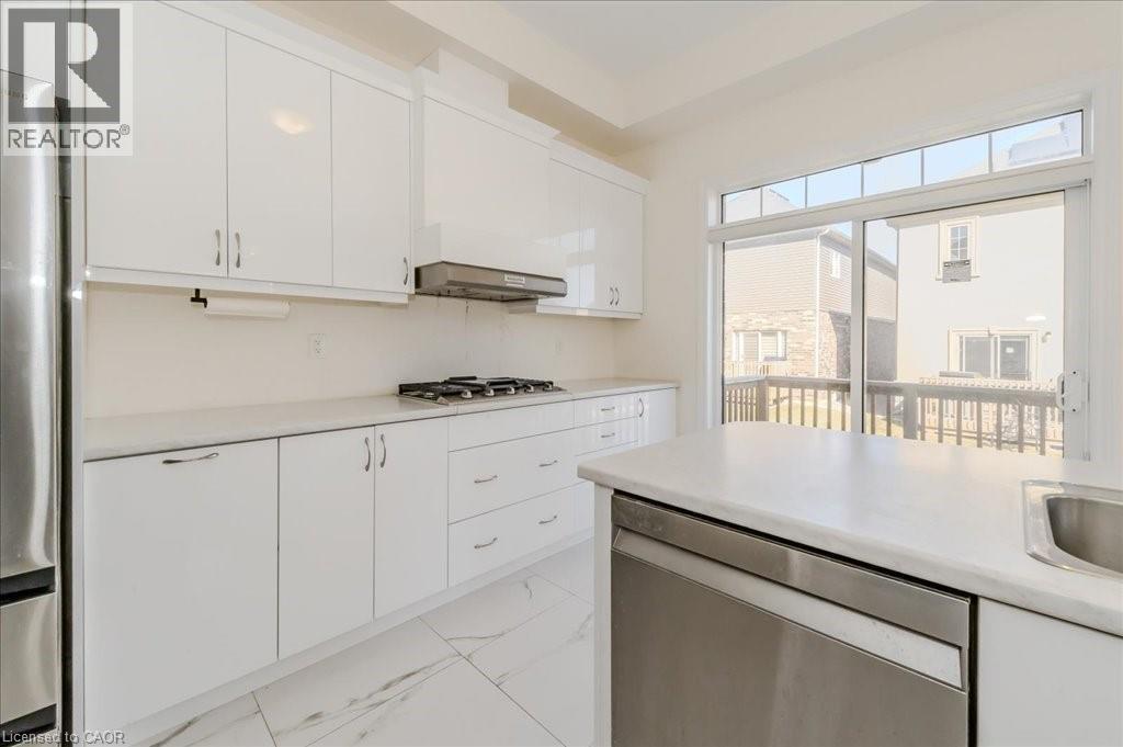 Kitchen with appliances with stainless steel finishes, white cabinetry, light countertops, light marble finish flooring, and range hood - 35 Hitchman Street, Paris, ON - Indoor Photo Showing Kitchen