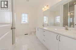 Bathroom with double vanity, a marble finish shower, and light marble finish flooring -