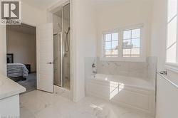 Full bathroom featuring ensuite bathroom, light marble finish flooring, a garden tub, a marble finish shower, and vanity -