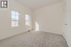 Spare room featuring light carpet and baseboards -