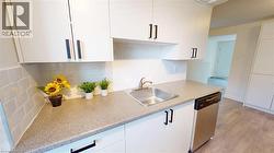 Kitchen with light wood-type flooring, white cabinetry, stainless steel dishwasher, and tasteful backsplash -