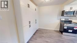 Kitchen featuring stainless steel appliances, light wood-type flooring, backsplash, and white cabinetry -