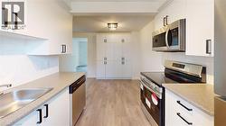 Kitchen featuring tasteful backsplash, stainless steel appliances, light wood-style flooring, and white cabinets -