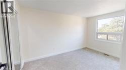 Unfurnished bedroom with light colored carpet and baseboards -