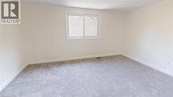 Empty room with light colored carpet and baseboards -