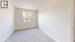 Spare room featuring light carpet and baseboards -