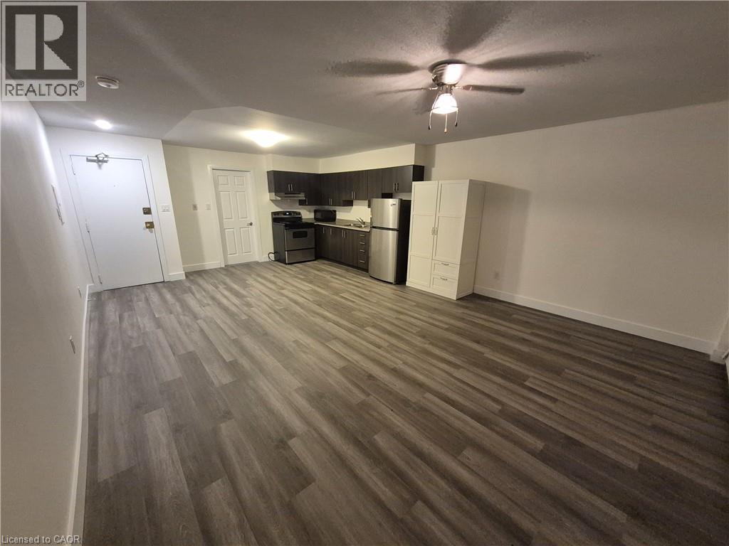 Kitchen with stainless steel appliances, dark wood-style flooring, light countertops, open floor plan, and ceiling fan - 27 Bridge Street Unit# 107, Brantford, ON - Indoor Photo Showing Other Room