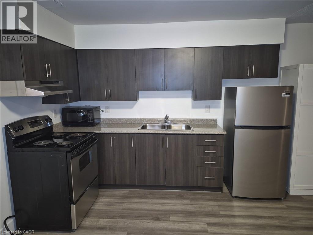 Kitchen with black appliances, dark wood-type flooring, dark brown cabinets, and light countertops - 27 Bridge Street Unit# 107, Brantford, ON - Indoor Photo Showing Kitchen With Double Sink