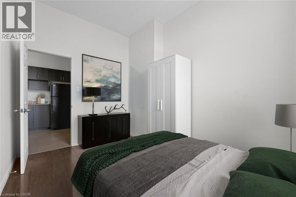 Bedroom with freestanding refrigerator and dark wood finished floors - 27 Bridge Street Unit# 305, Brantford, ON - Indoor Photo Showing Bedroom