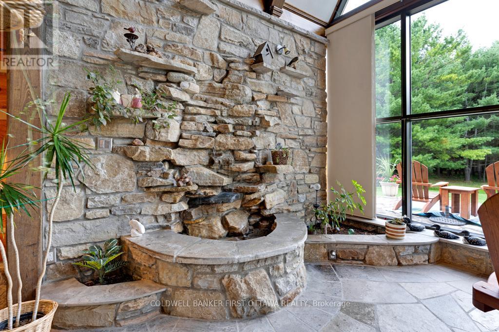 Solarium rock wall with decorative waterfall - 2499 Bathurst Concession 2 Road, Tay Valley, ON - Indoor Photo Showing Other Room With Fireplace
