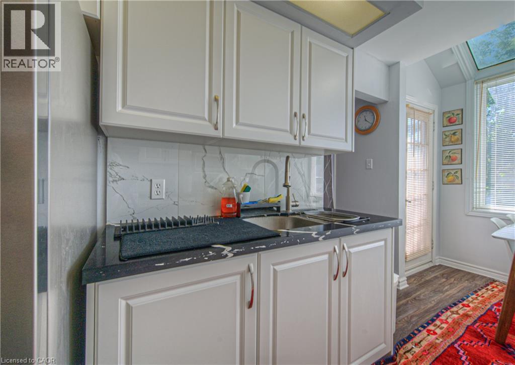 Kitchen featuring tasteful backsplash, white cabinets, wood finished floors, dark stone counters, and stainless steel fridge - 310 Christopher Drive Unit# 15, Cambridge, ON - Indoor Photo Showing Kitchen With Double Sink