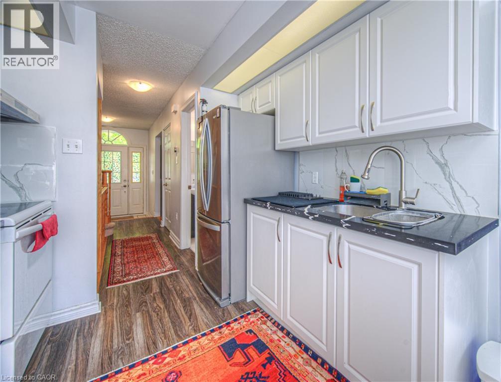 Kitchen with a textured ceiling, electric range, white cabinetry, dark wood-style flooring, and tasteful backsplash - 310 Christopher Drive Unit# 15, Cambridge, ON - Indoor Photo Showing Kitchen With Double Sink