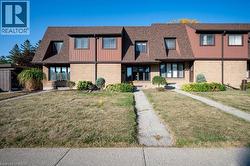 View of front of property featuring roof with shingles, a front lawn, and brick siding -