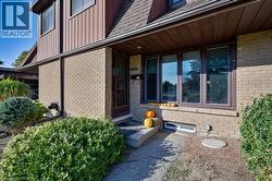 Doorway to property featuring brick siding, a shingled roof, and board and batten siding -