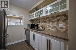 Kitchen with white cabinetry, glass insert cabinets, tasteful backsplash, appliances with stainless steel finishes, and dark wood-style floors -