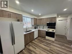 Kitchen featuring white appliances, dark wood finished floors, tasteful backsplash, recessed lighting, and brown cabinets -