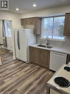 Kitchen featuring white appliances, brown cabinets, dark wood finished floors, backsplash, and recessed lighting -