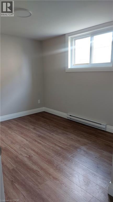 Spare room featuring a baseboard radiator and light wood-style flooring - 106 Chandler Drive Unit# 1, Kitchener, ON - Indoor Photo Showing Other Room