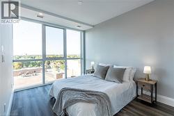 Bedroom with floor to ceiling windows, dark wood-type flooring, and recessed lighting -