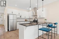 Kitchen with appliances with stainless steel finishes, white cabinets, a peninsula, decorative light fixtures, and recessed lighting -