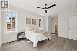 Bedroom with a closet, light wood finished floors, ceiling fan, and ensuite bathroom -
