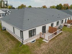 Back of property with a wooden deck, a lawn, and a shingled roof -