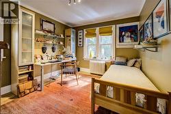 Bedroom with ornamental molding, a desk, light wood-style floors, and radiator heating unit -