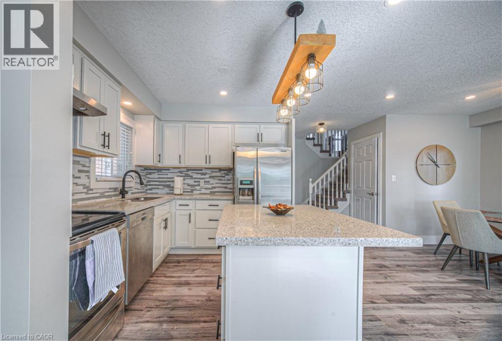 Kitchen with appliances with stainless steel finishes, a textured ceiling, a kitchen island, tasteful backsplash, and dark wood finished floors - 220 Sienna Crescent, Kitchener, ON - Indoor Photo Showing Kitchen With Stainless Steel Kitchen With Upgraded Kitchen