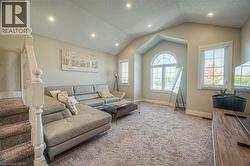 Carpeted living room with a textured ceiling, recessed lighting, vaulted ceiling, and stairs -