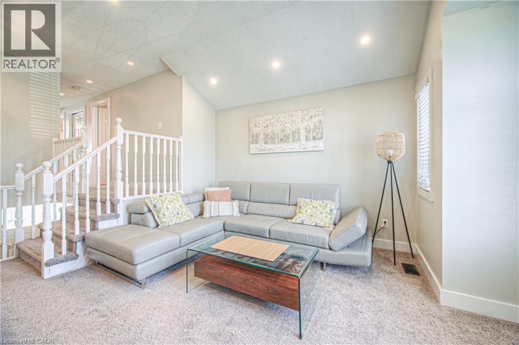 Carpeted living room with vaulted ceiling, recessed lighting, and stairway - 220 Sienna Crescent, Kitchener, ON - Indoor Photo Showing Living Room