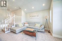 Carpeted living room with vaulted ceiling, recessed lighting, and stairway -
