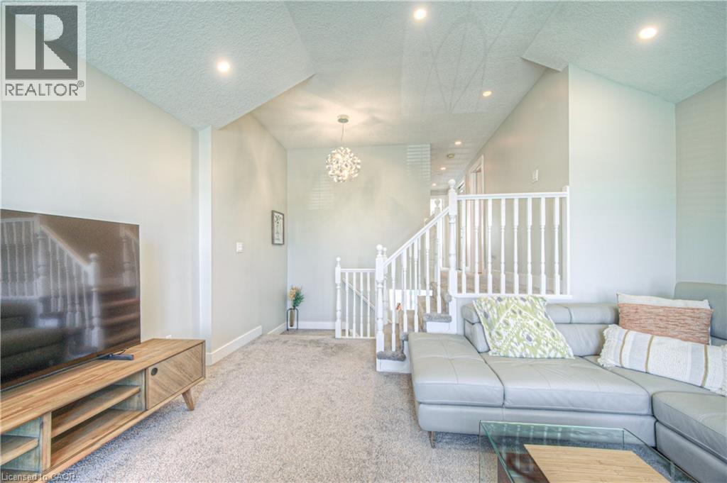 Carpeted living area with a textured ceiling, recessed lighting, and a chandelier - 220 Sienna Crescent, Kitchener, ON - Indoor Photo Showing Living Room