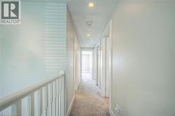 Corridor with light carpet, a textured ceiling, recessed lighting, and an upstairs landing -