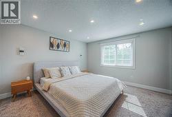 Bedroom with carpet, a textured ceiling, and recessed lighting -