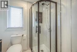 Full bathroom with a marble finish shower and toilet -