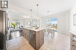 Kitchen with appliances with stainless steel finishes, hanging light fixtures, light tile patterned floors, and plenty of natural light -