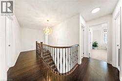Hall with an upstairs landing, a chandelier, and dark wood-style flooring -