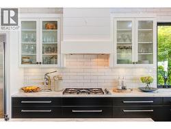 Two tone cabinetry plus glass front upper cabinets, tile backsplash and marble counters -