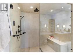 glass and tile walk in steam shower with quartz clad bench. -