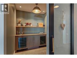 Wine room: located just off of the sunken Great room with glass front barn style door, two integrated glass front beverage fridges, floating wood shelving and custom pot and pendant lighting. -